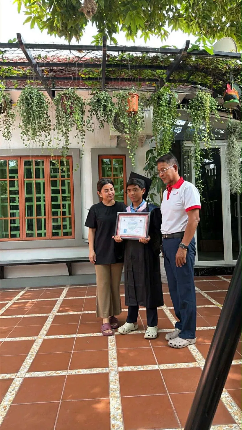 Kong Chea Sasda with family, holding graduation certificate