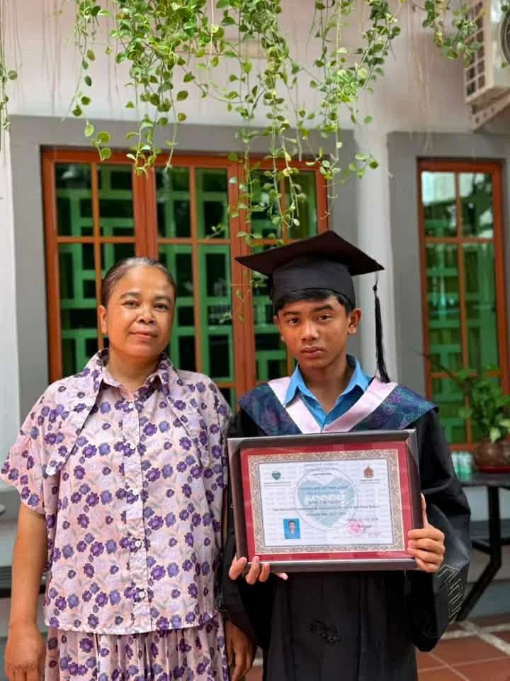 Sasda with mom, holding graduation certificate
